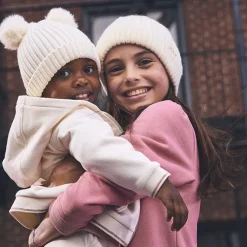 Muts van geribd gebreid met pompons voor babymeisje